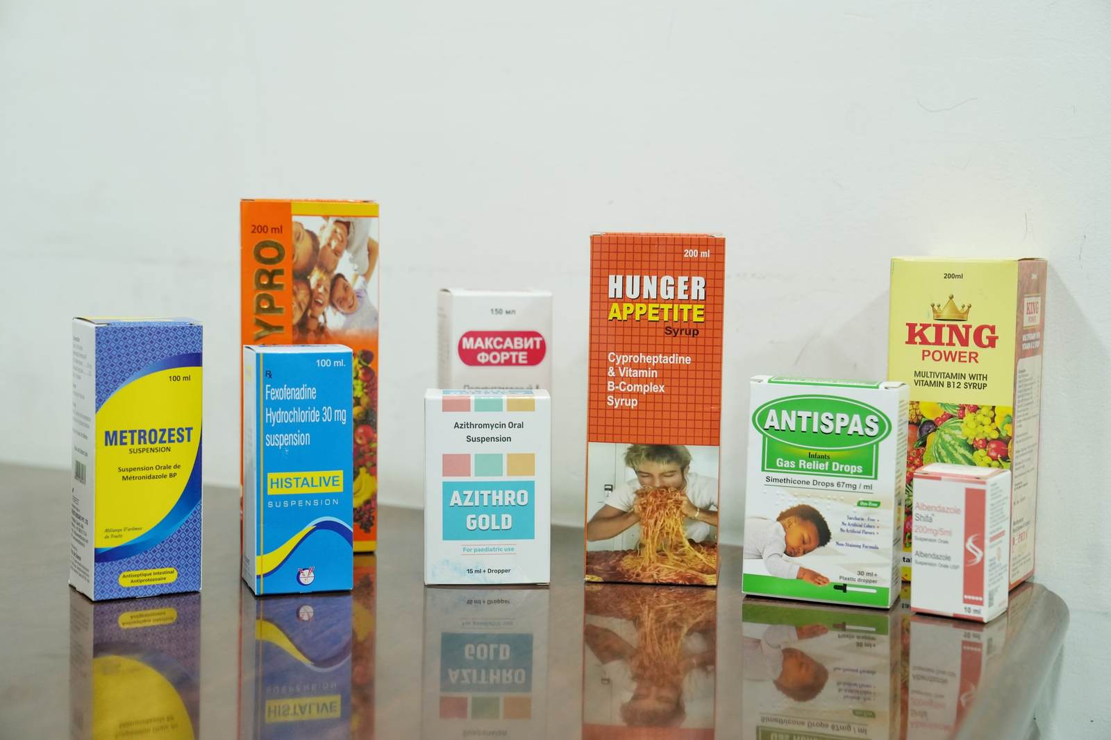 A range of liquid oral product cartons including Metrozest, Histalive, Azithro Gold, Hunger Appetite, Antispas and King Power arranged on a table